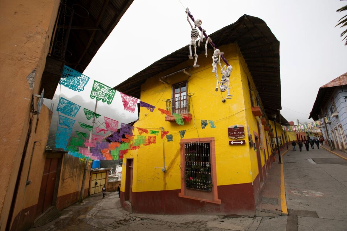 casa de fachada naranja en una calle decorada con papel picado 