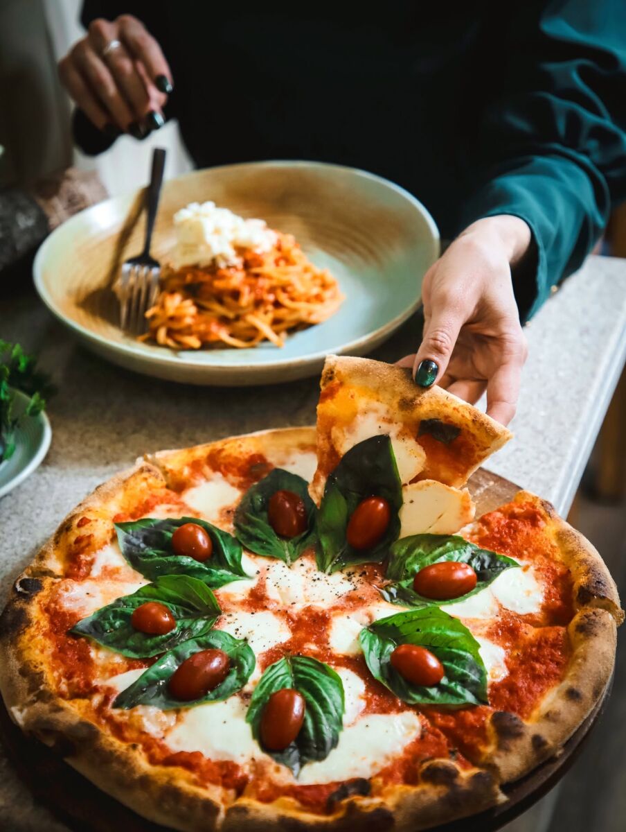 mujer comiendo pizza y pasta