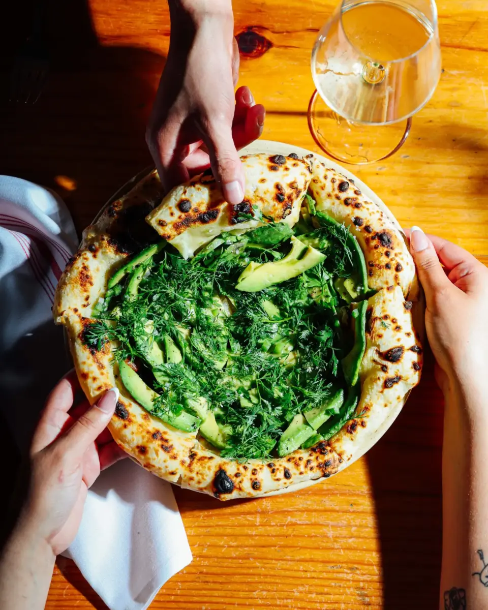 pizza de aguacate con aderezo partida en cuatro