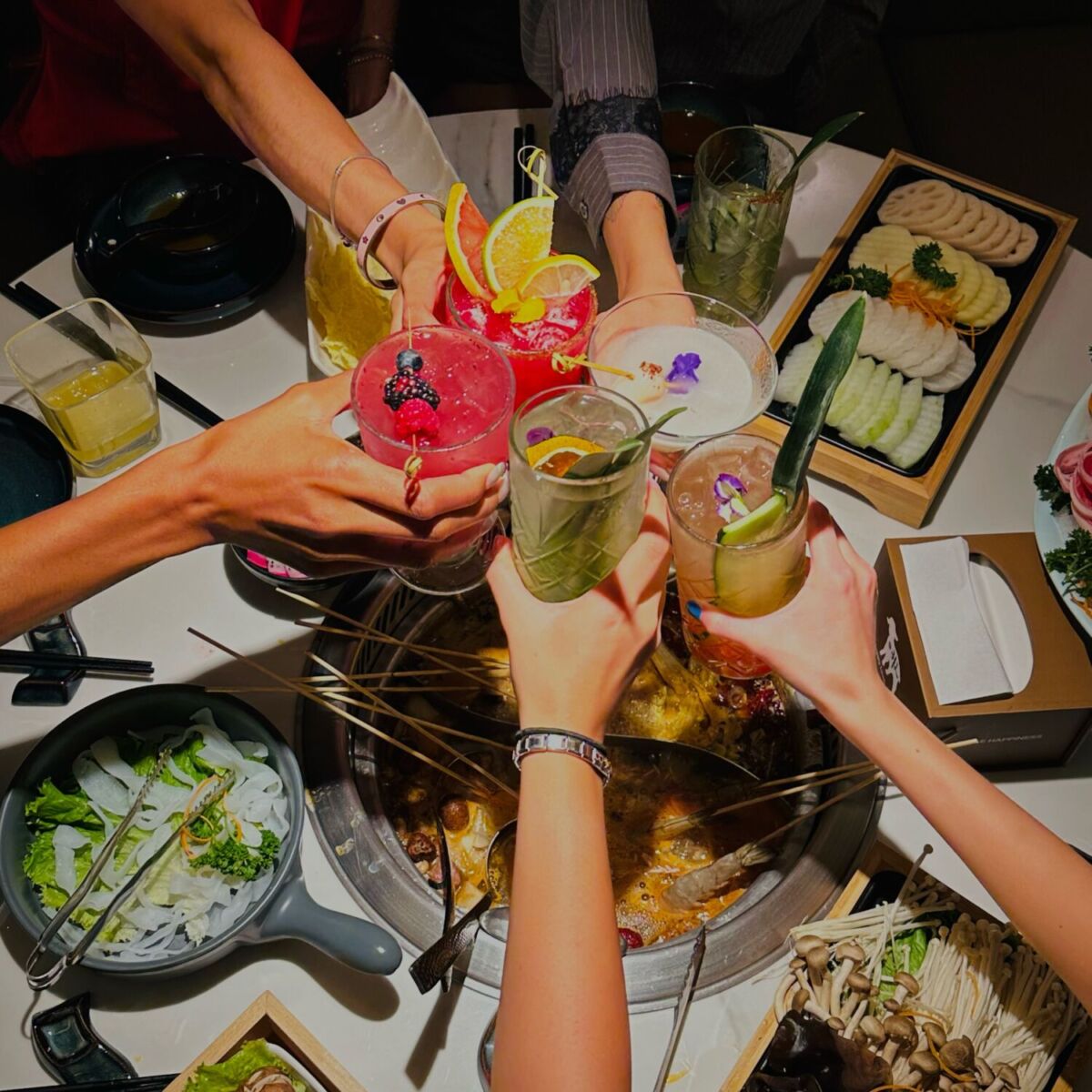 personas brindando sobre un hot pot en restaurante