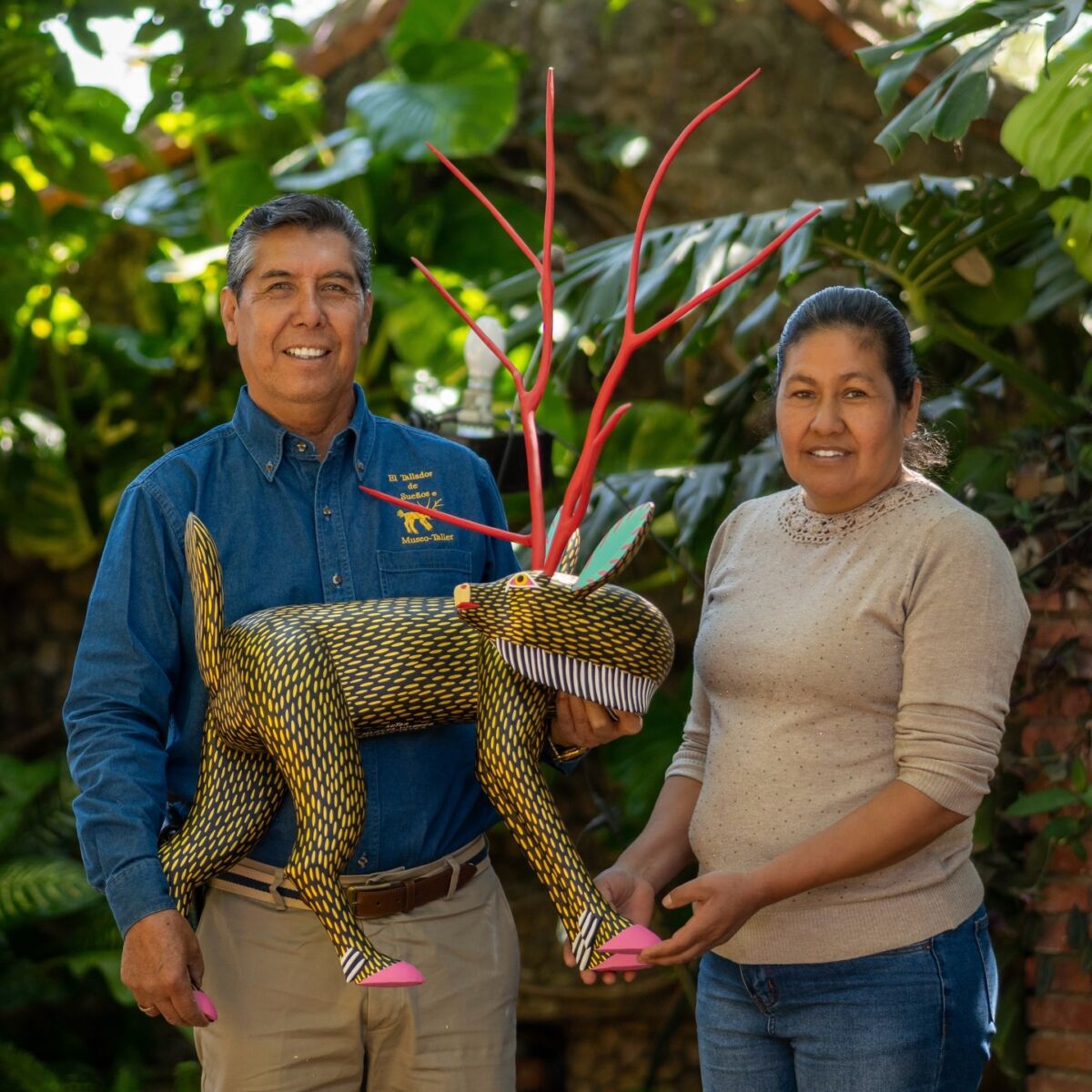 Isaías Jiménez Hernández y su esposa con animal fantástico tallado en madera