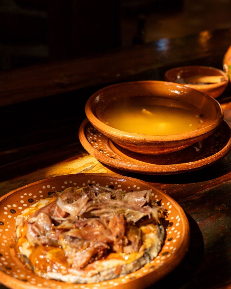 taco de barbacoa con caldo de carne en platos de barro