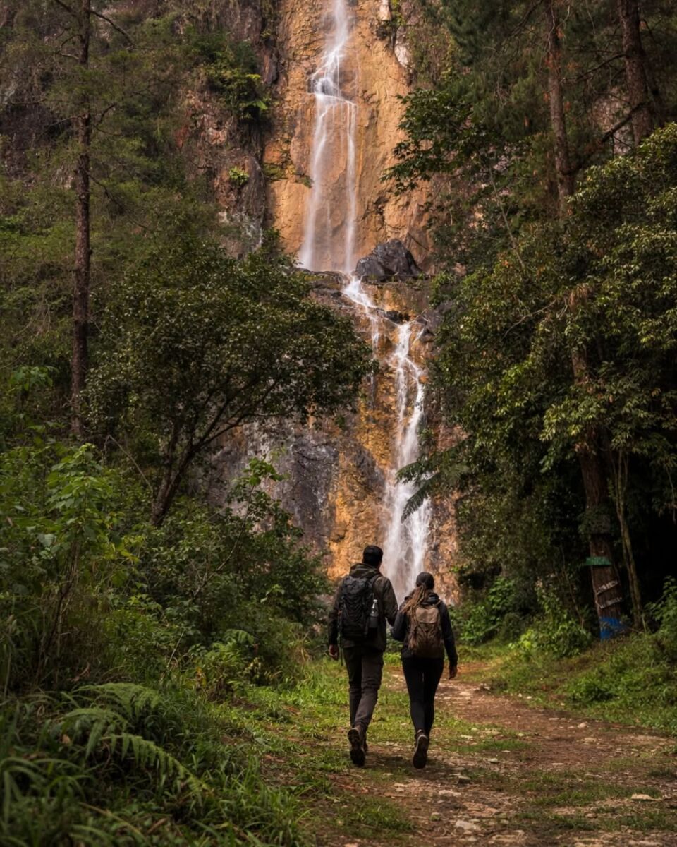 pareja caminando hacia una cascada