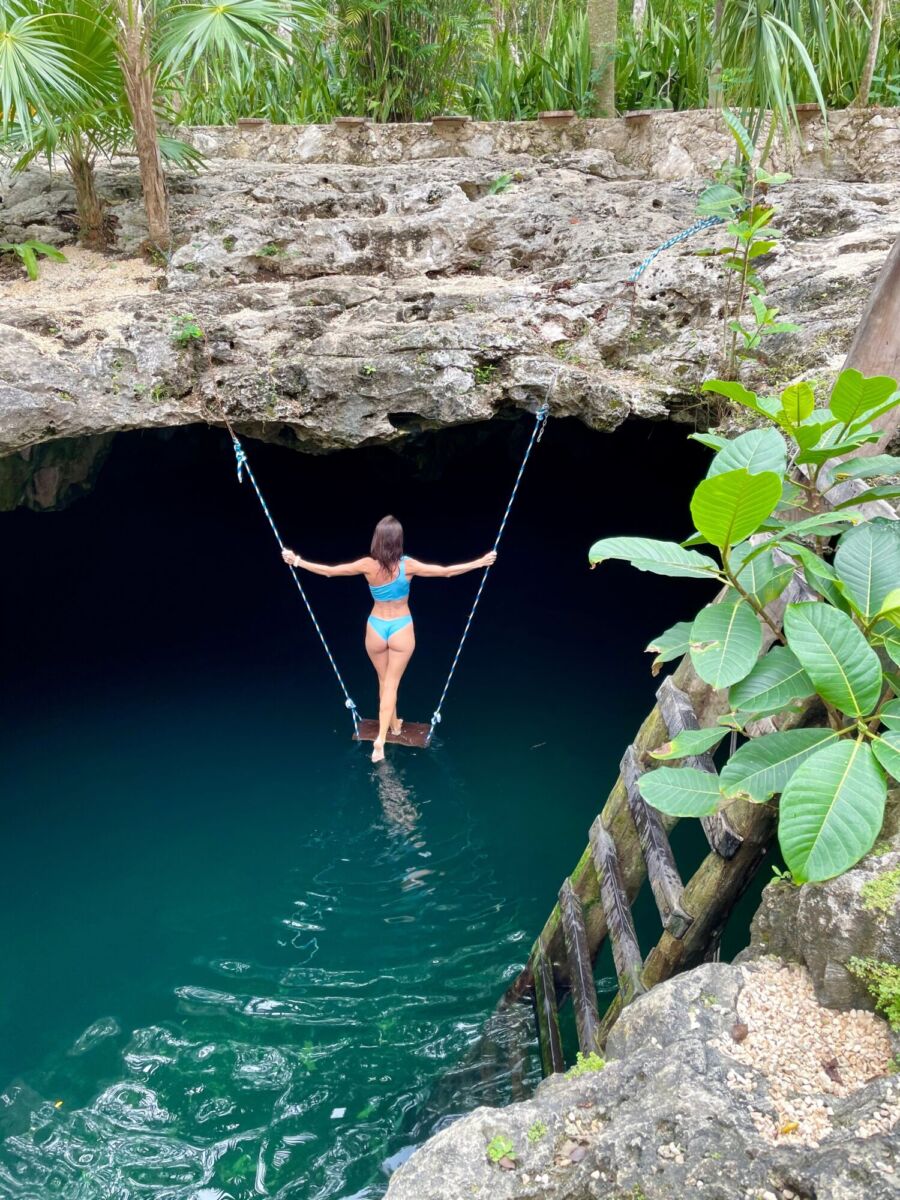 mujer parada en un columpio sobre un cenote