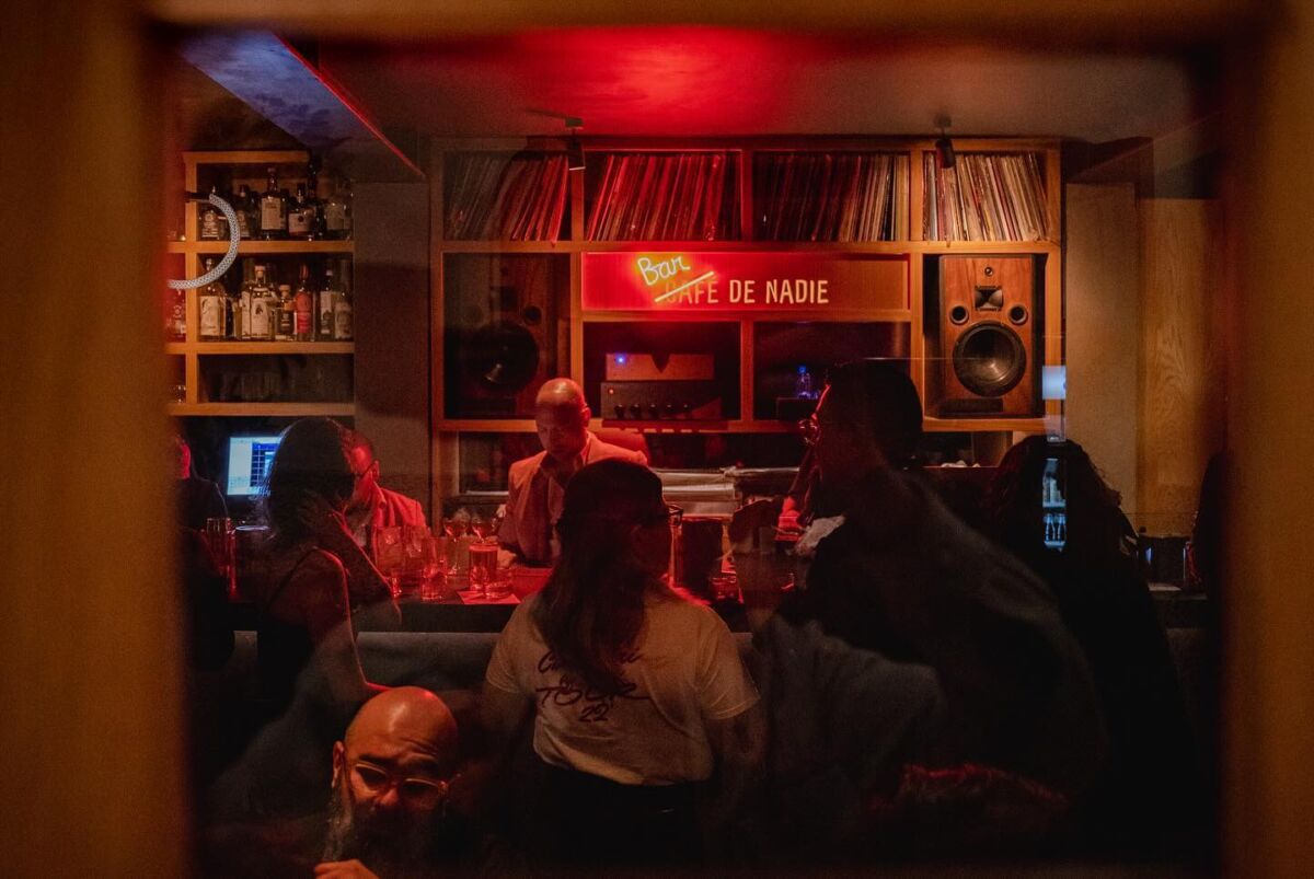 café de nadie con vinilos y personas tomando cócteles