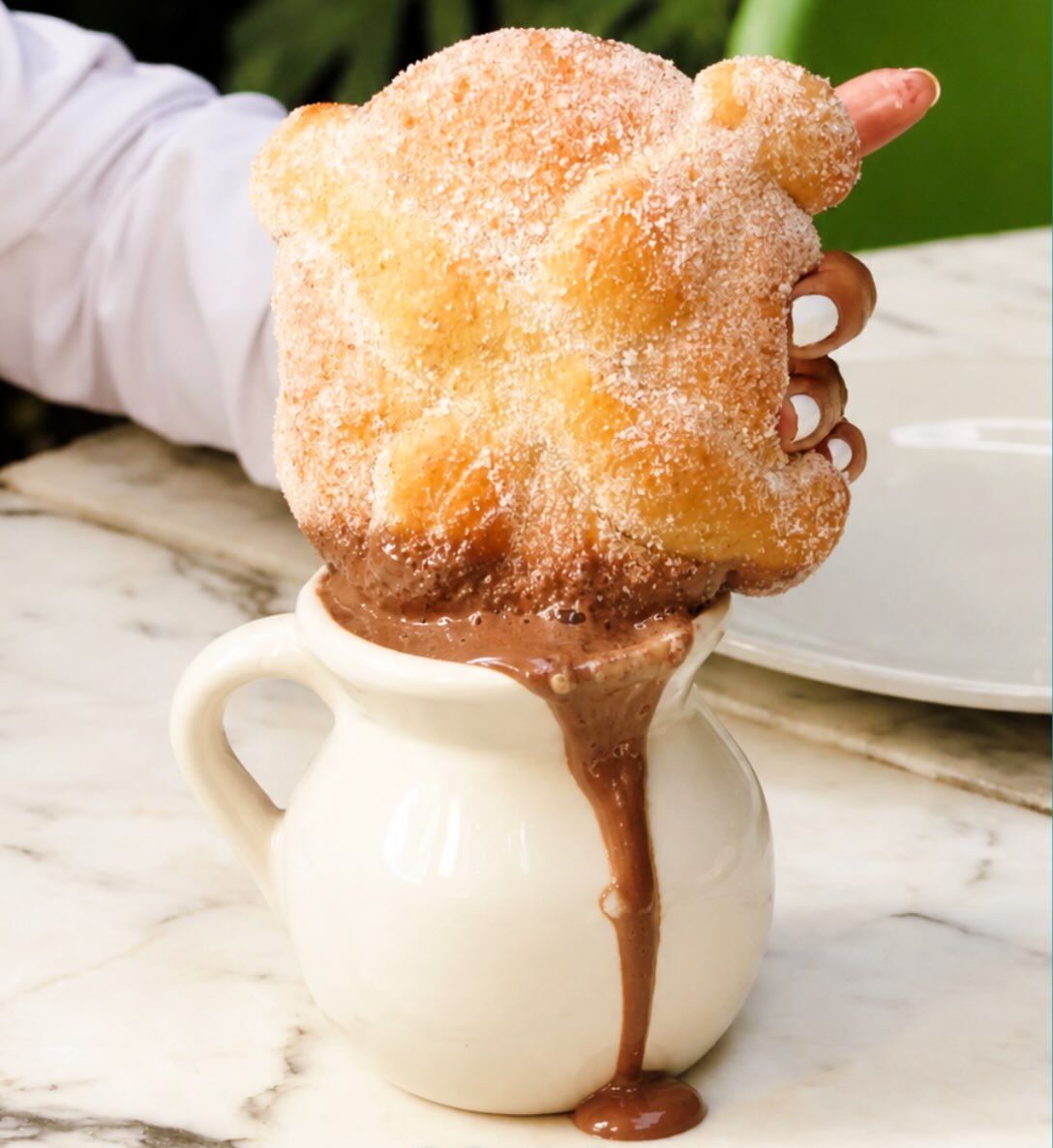 mujer remojando un pan de muerto en chocolate caliente