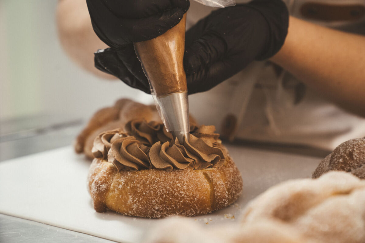 persona rellenando un pan de muerto 