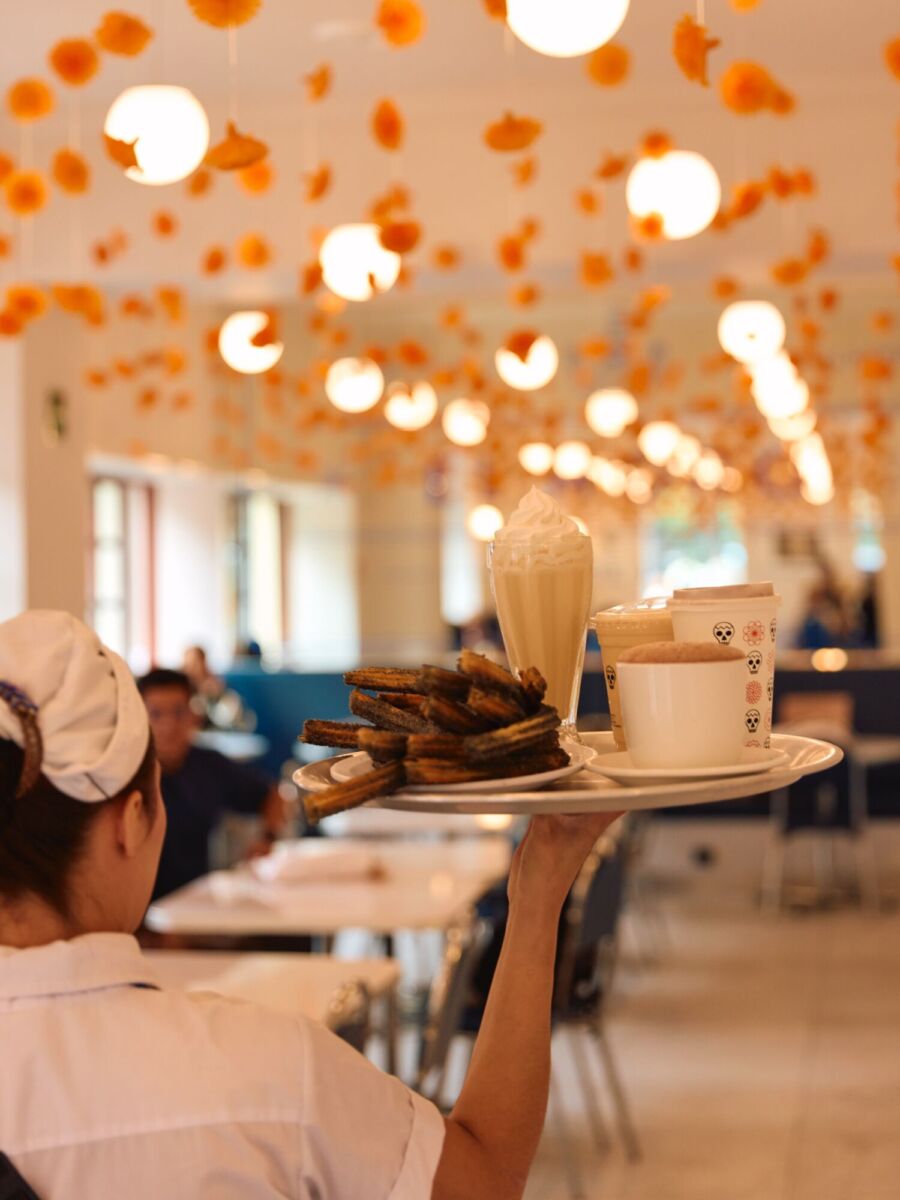 mesera llevan una charola con postres de sabor pan de muerto 